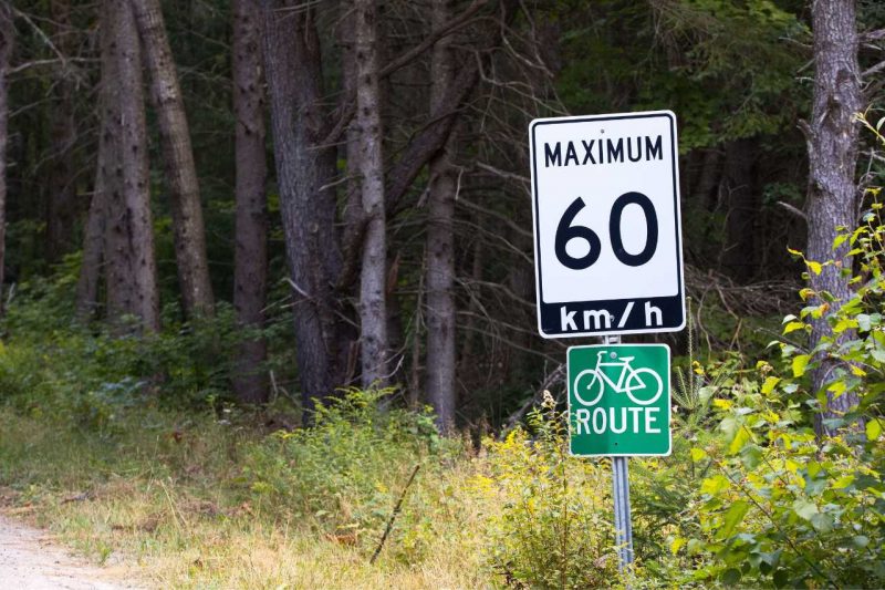 A speed limit post that says 60 km per hour, on the side of a road.