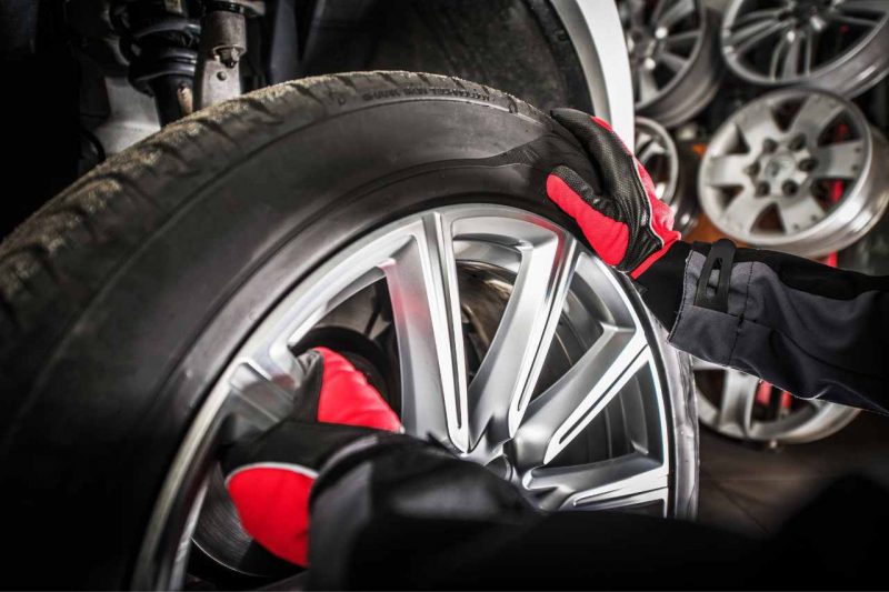 A Nissan auto mechanic performs a tire swap on a vehicle.