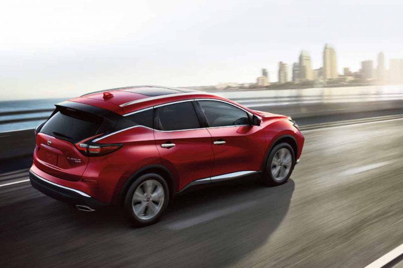 The 2024 red Nissan Murano drives down a sunny highway.