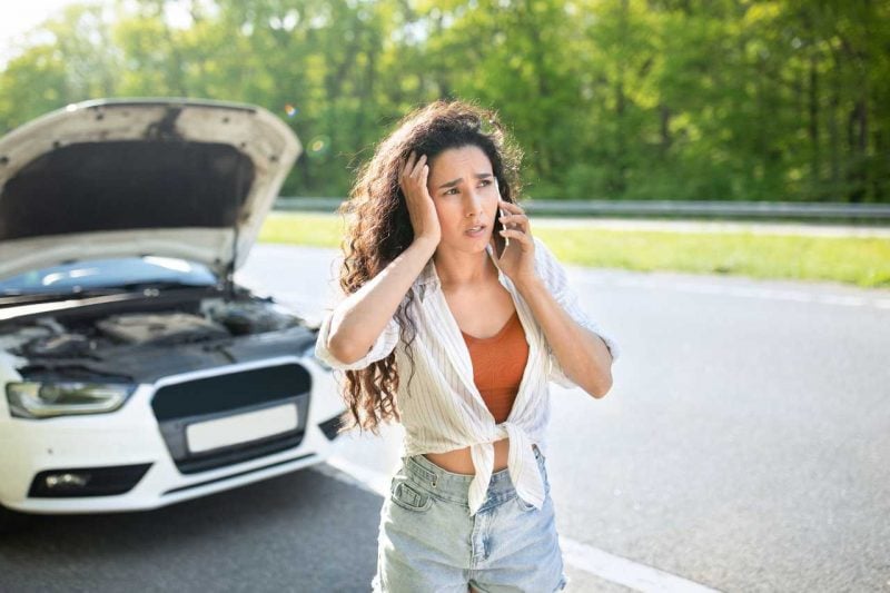 A young woman calls for help as she has engine trouble on the side of the road.