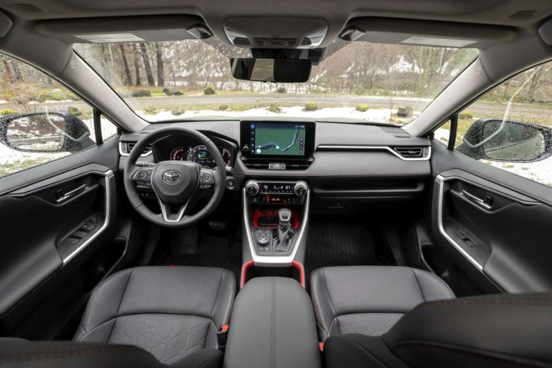 The interior view of the 2024 Toyota RAV4, showcasing the touchscreen, steering wheel and driver's area.