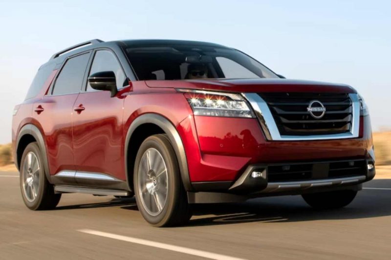 A 2024 Nissan Pathfinder in red driving along a sunny highway.