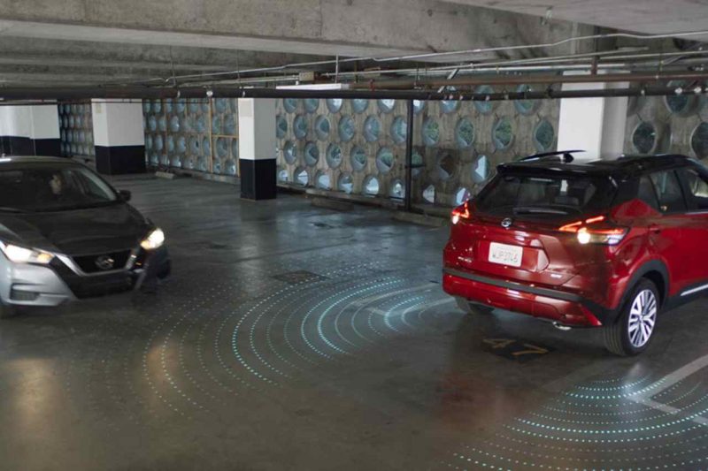 A vehicle driving past a parked vehicle in a parking garage, with a diagram showcasing the Rear Detection Safety system of the parked car.