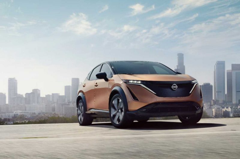 The 2024 Nissan Ariya is parked on a concrete road overlooking the city of Toronto on a sunny afternoon.