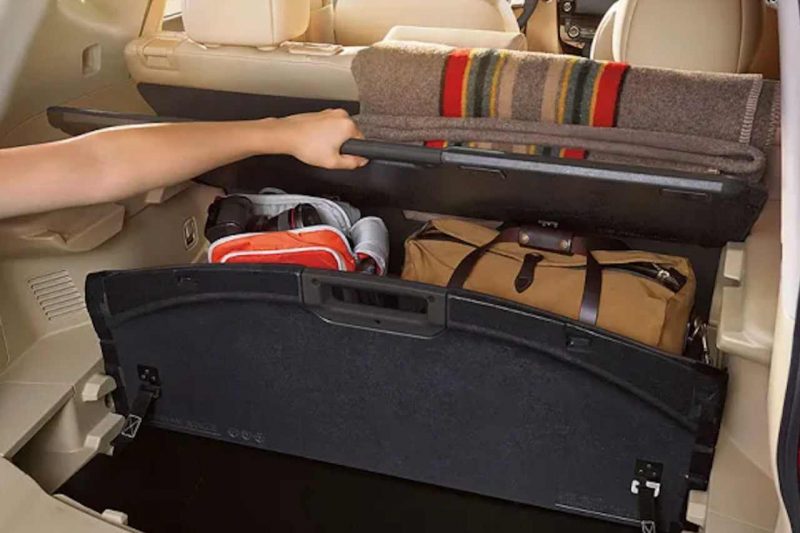 An individual lifts up the Divide-N-Hide cargo accessory to reveal storage options in the Nissan Rogue.