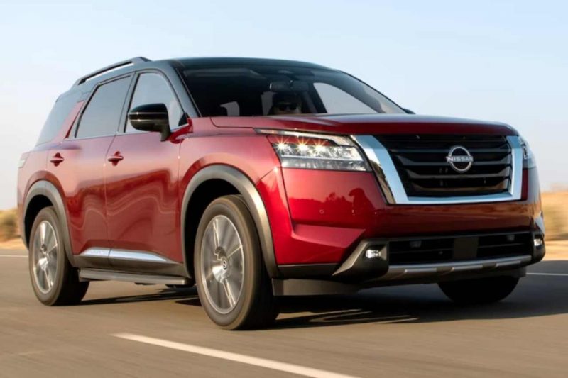 A red Nissan Pathfinder SUV, one of our dog-friendly cars, drives down a sunny highway.