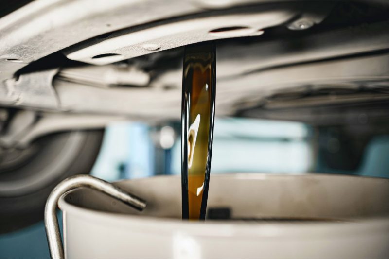 Old oil draining from the bottom of a car during an oil change.