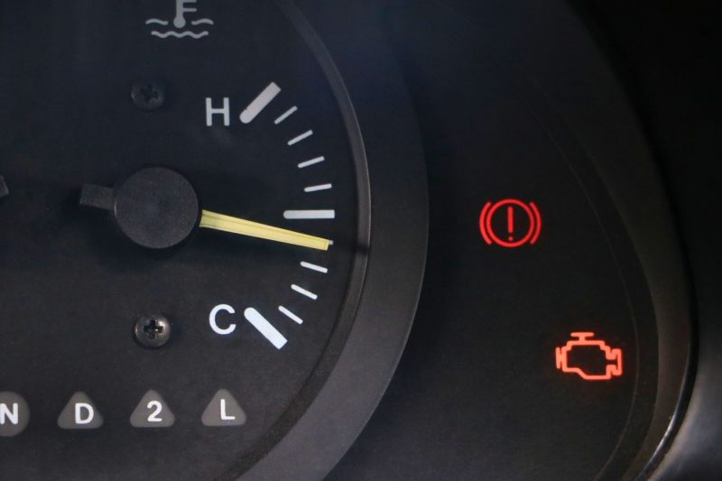 A close-up view of a vehicle's dashboard displaying an engine light warning.