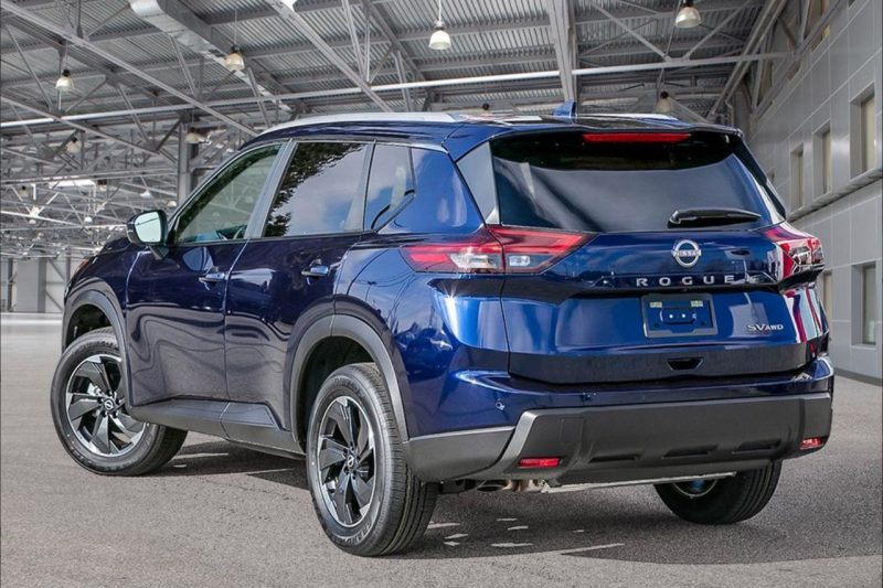 A brand new Nissan SUV in blue is posed in an empty warehouse, ready for sale.
