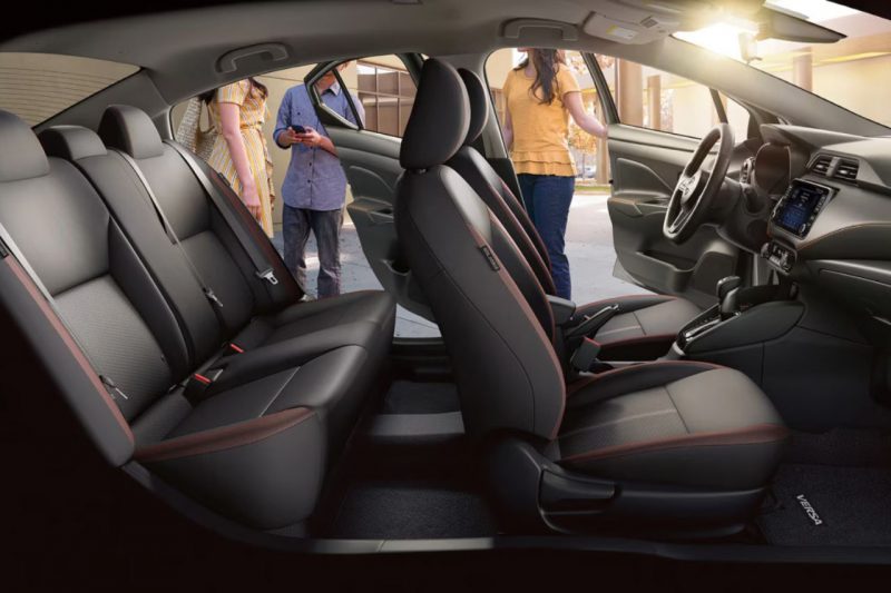 The interior of a Nissan vehicle, showcasing the front and back row of the car.