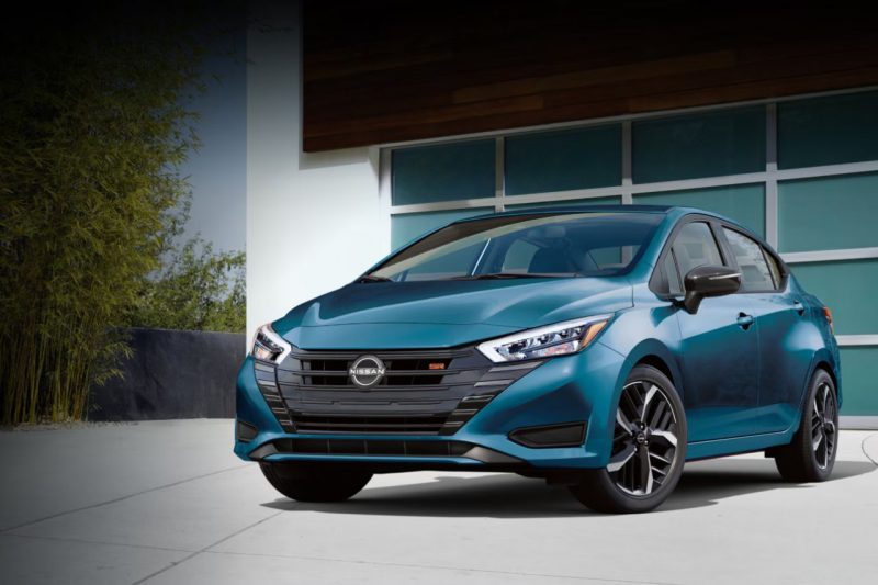 The all-new 2025 Nissan Versa in a blue colour sits outside a modern home's garage.