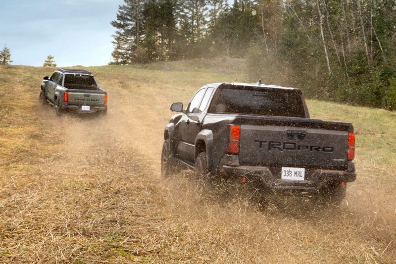 Two Toyota trucks drive around on a dirt field.