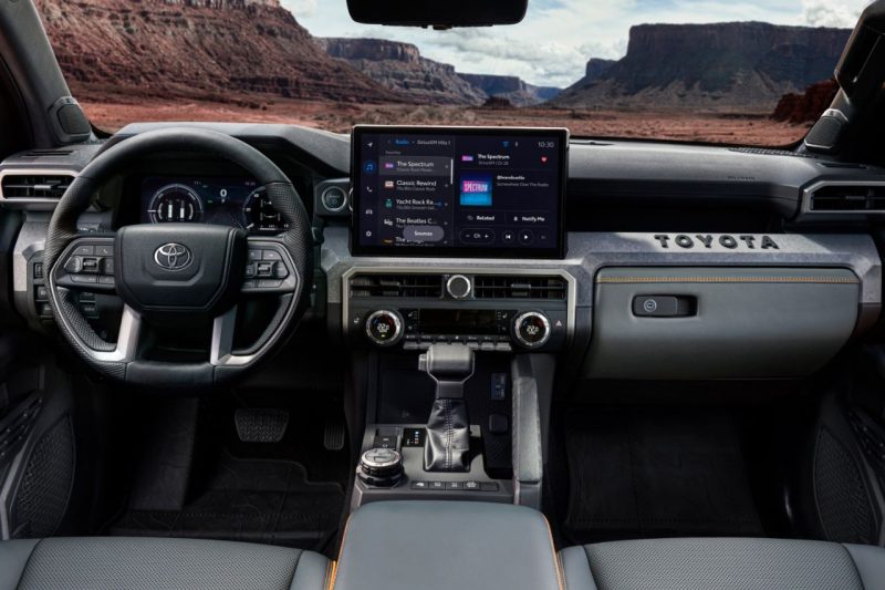 The interior of a truck cabin, showing the steering wheel, touchscreen display and windshield.