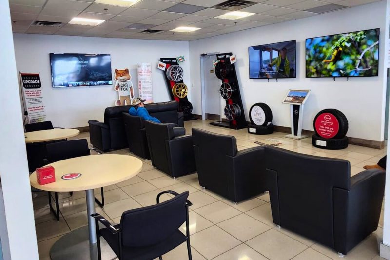 A comfy lounge with black leather chairs, three televisions, and a complimentary coffee machine.