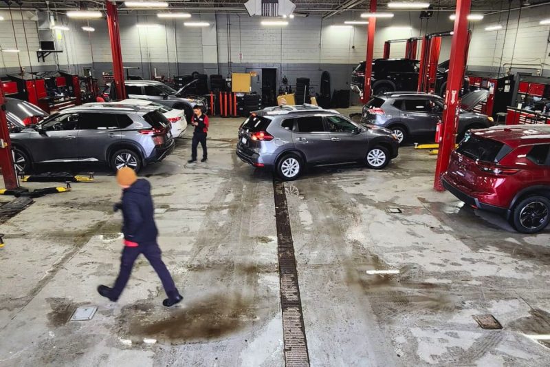 The interior of the Woodbine Nissan service centre, with multiple cars being worked on by technicians.