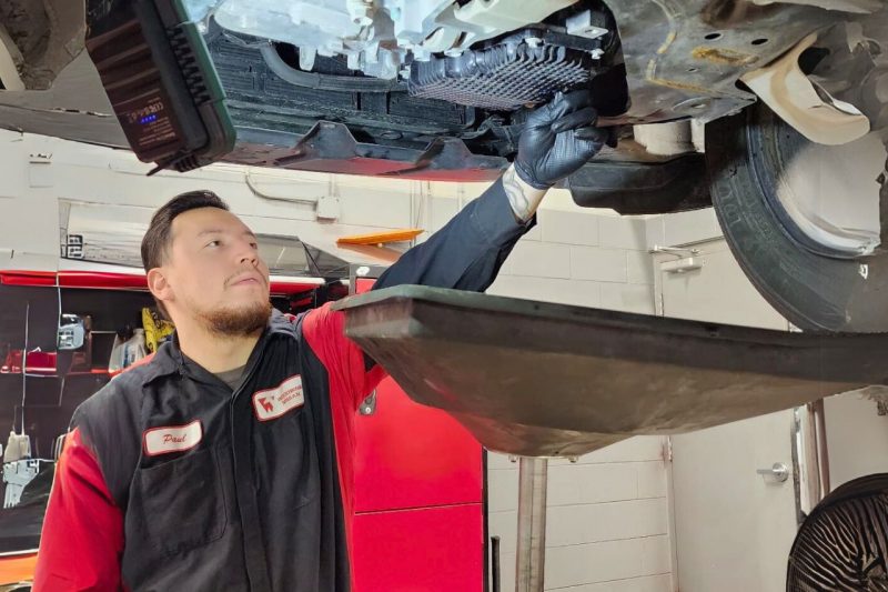 A technician works underneath a vehicle performing a Woodbine Nissan oil change.