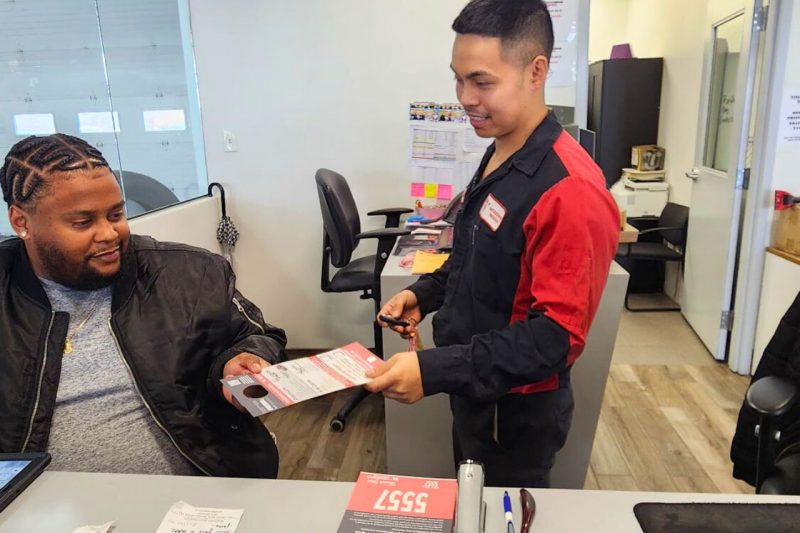 A Nissan service technician hands over the keys to a service advisor after a service has been completed.