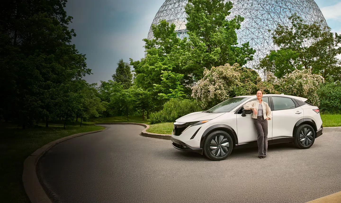 2026 Nissan Ariya electric with driver in an urban and green setting.