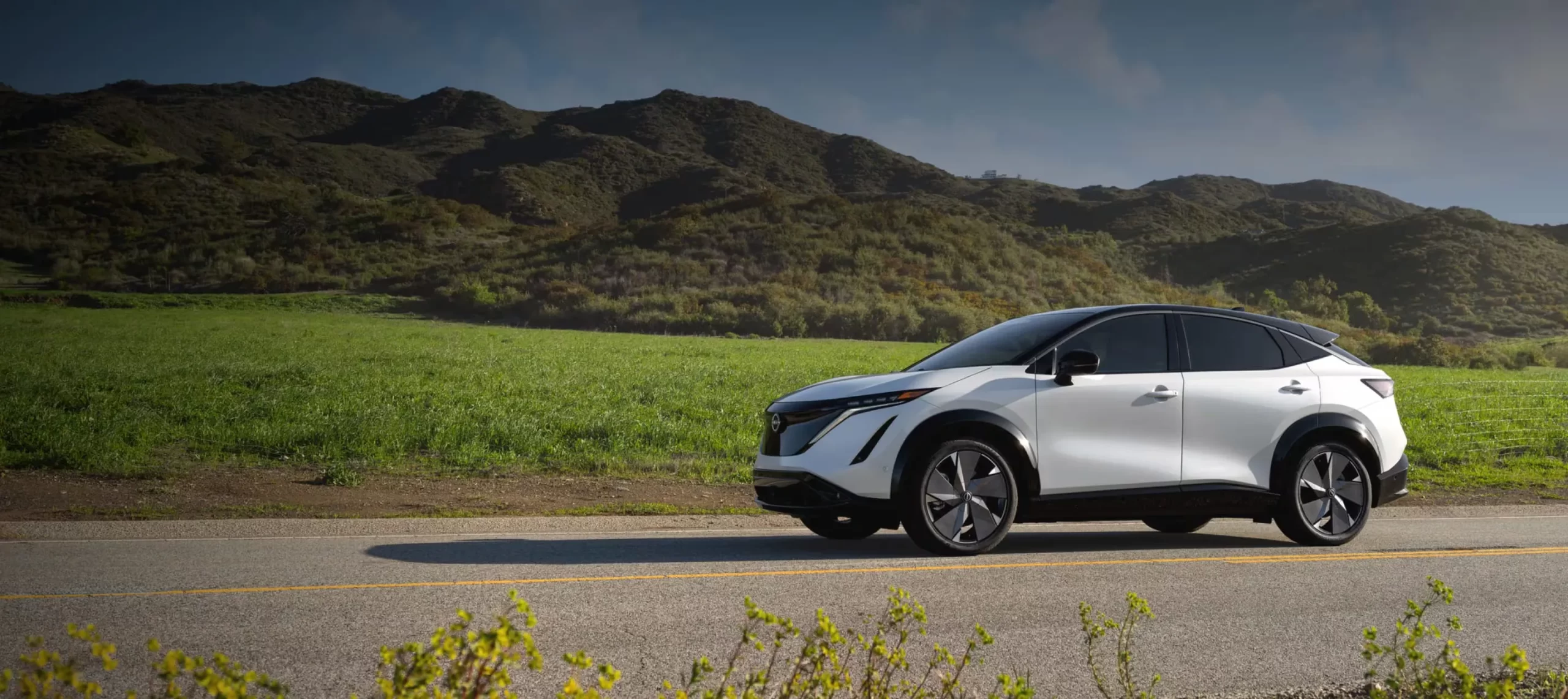 2026 Nissan Ariya electric on a scenic road to conclude the specs and pricing article.