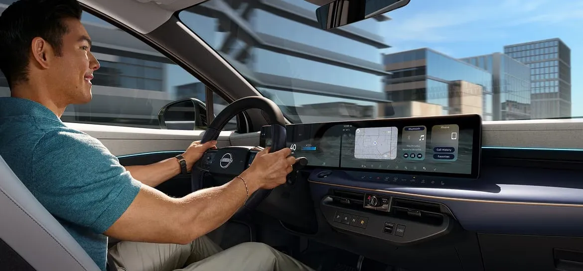 Driver at the wheel of the 2026 Nissan Leaf with a modern dashboard.