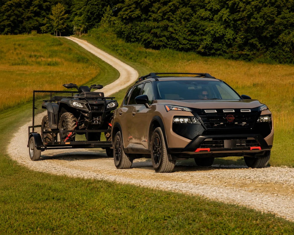 Nissan Rogue 2026 remorquant un VTT sur un chemin de gravier.