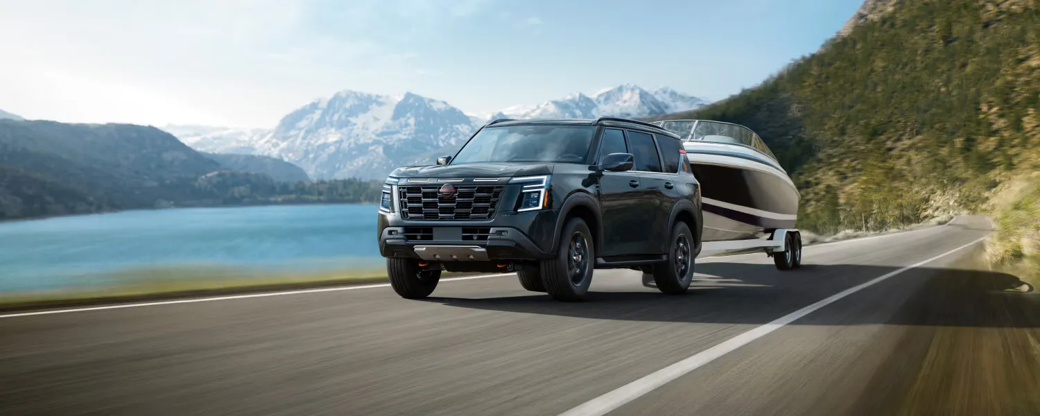 2026 Nissan Armada towing a boat on a mountain road.