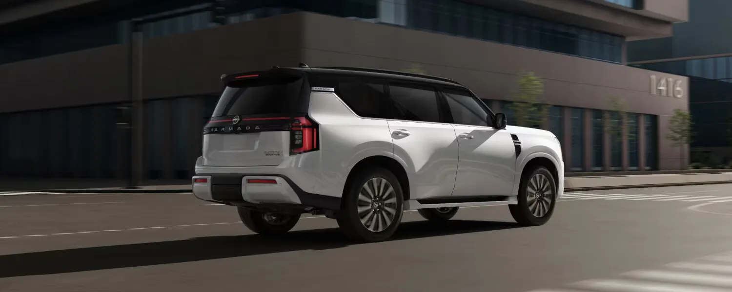 Rear view of the white 2026 Nissan Armada driving in the city.