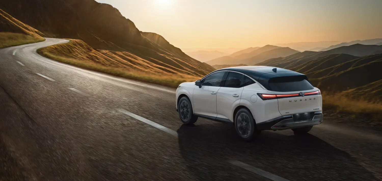 White 2026 Nissan Murano driving on a scenic mountain road.