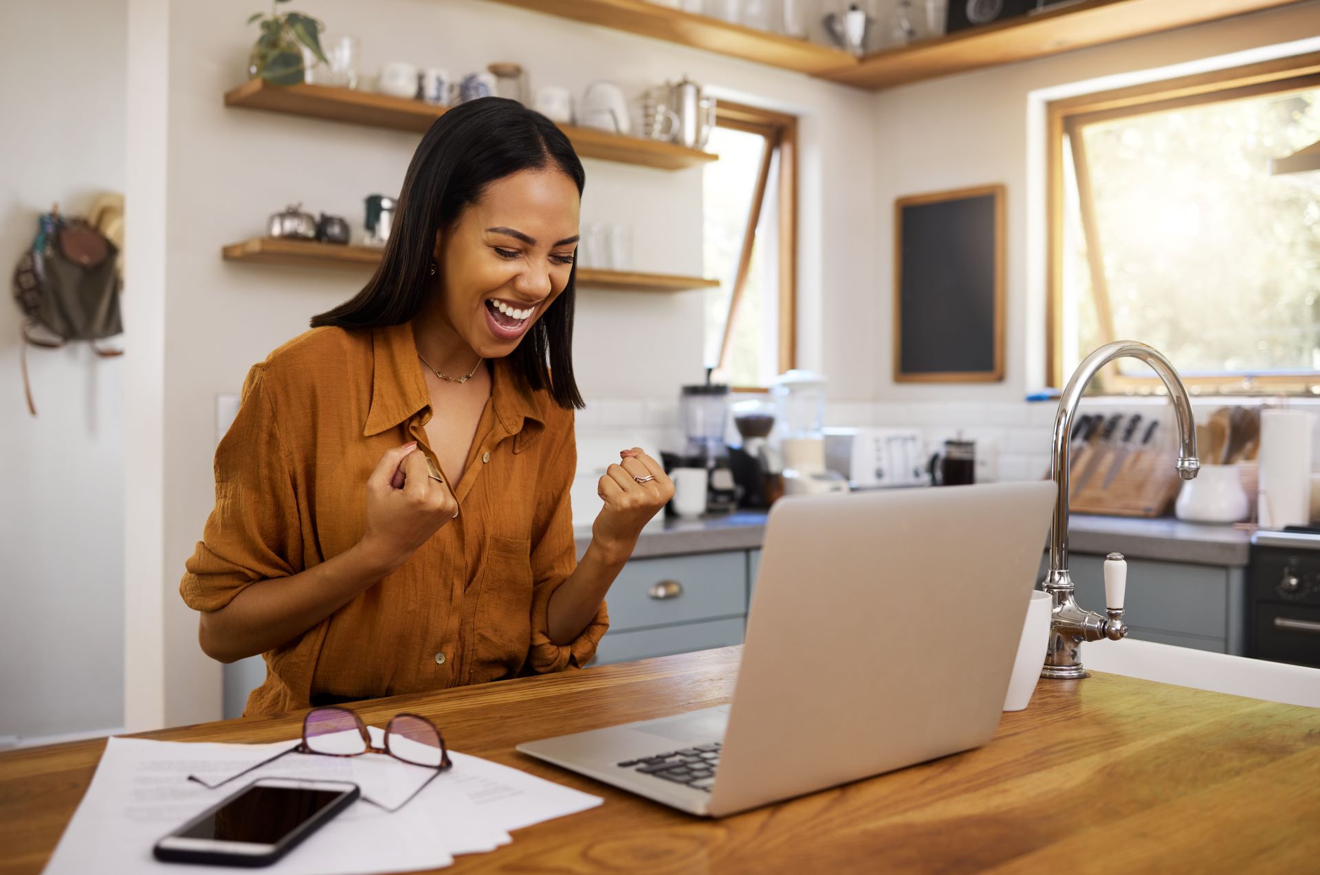 Used auto loan customer pumping fists in kitchen celebrating car loan approval